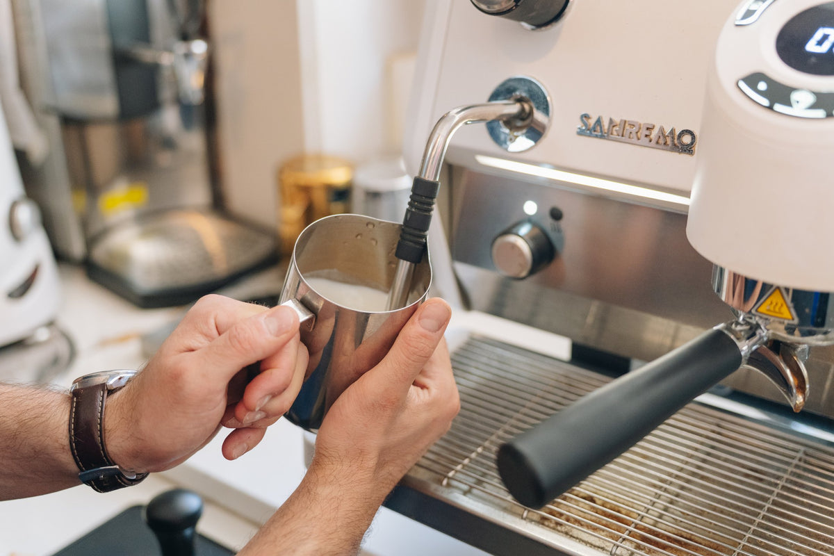 A barista steaming milk at the café espresso machine